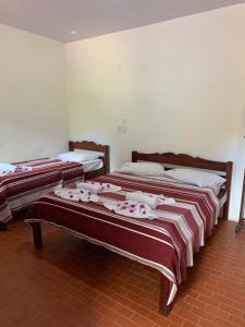 two beds in a room with red and white blankets at Estancia Vale das Flores in Pacoti