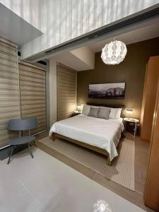 a bedroom with a large bed and a chandelier at Tranquil Manor at Uptown BGC in Manila