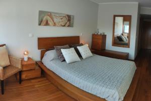 - une chambre avec un lit, une chaise et un miroir dans l'établissement Furadouro Pool&Beach Apart, à Ovar