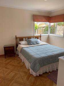 een slaapkamer met een bed met een blauw dekbed en een raam bij Casa para 4 personas, en El Quisco Norte in El Quisco