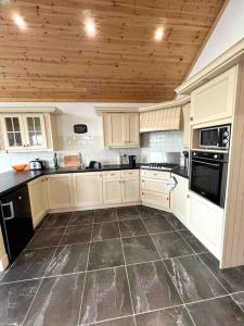 uma cozinha com armários brancos e piso em azulejo em Cheerful 2 bedroom cottage with free parking em Droíchead an Chláir
