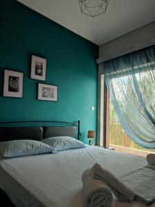 a bedroom with a bed with a blue wall and a window at Panorama house leika kalamatas in Kalamata