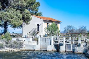 a building with a bridge over a body of water at MAS de COLOMINA Aigues-Mortes in Aigues-Mortes