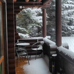 einen Balkon mit einem Tisch und Stühlen mit Schnee in der Unterkunft Шаленарозі in Myhowe