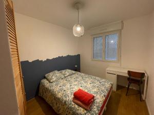 een slaapkamer met een bed met een rood kussen en een bureau bij Appartement spacieux. P gratuit.plage à 13 min in Brest
