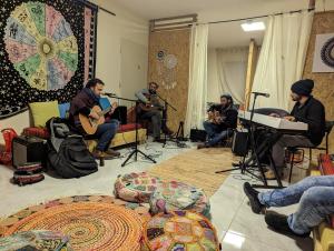 eine Gruppe von Menschen, die in einem Zimmer Musik spielen in der Unterkunft אשראם בכרמל - אכסניה in Dāliyat el Karmil