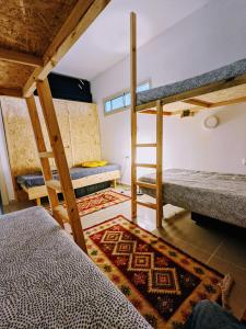 a room with three bunk beds and a rug at אשראם בכרמל - אכסניה in Dāliyat el Karmil
