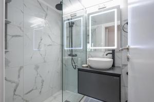 uma casa de banho com um lavatório e um chuveiro com um espelho. em Comfortable Apartment In Athens em Atenas