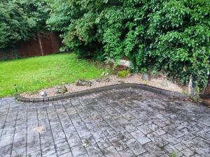 um jardim com um pátio de tijolos e um quintal em Serendipity em Manchester