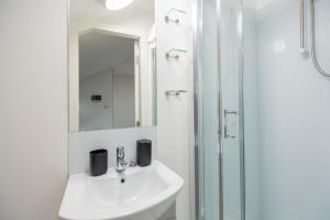 La salle de bains blanche est pourvue d'un lavabo et d'une douche. dans l'établissement Spacious and Modern studio in London G, à Londres