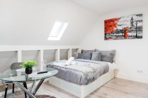 a white bedroom with a bed and a glass table at Spacious and Modern studio in London G in London