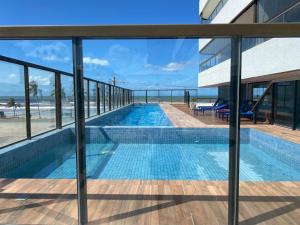 a swimming pool with a view of the ocean from a building at Apartamento na Praia dos Milionários in Ilhéus