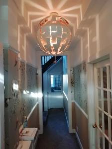 a hallway with a chandelier hanging from a ceiling at Carvetii - Halite House - 3 bed House sleeps up to 5 people in Tillicoultry