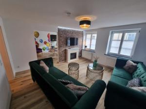 ein Wohnzimmer mit 2 grünen Sofas und einem Kamin in der Unterkunft Hufschmieds Bleibe in Passau