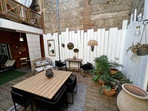 een patio met een houten tafel en stoelen en een hek bij Le Paillé de Torreilles in Torreilles