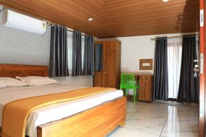 een slaapkamer met een bed en een groene stoel bij Bliss Homestay Munroe Island in Munroe Island