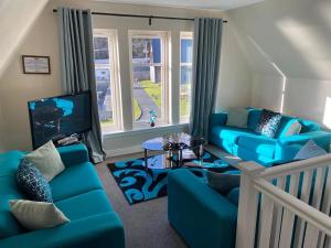 a living room with blue couches and a tv at Pheasant lodge - Balmaha 3 bed in Glasgow