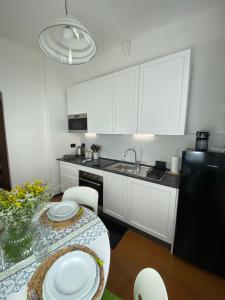 a kitchen with white cabinets and a table with plates on it at Appartamento Nonna Lidia in Chiavari