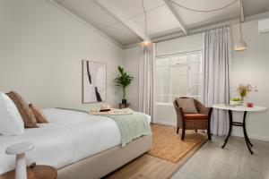 a bedroom with a bed and a table and a chair at Neighbourgood Franschhoek in Franschhoek