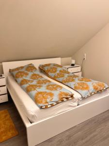 Haus am Wald في Schrozberg: سرير أبيض مع لحاف برتقالي وبيض