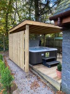 um barracão de madeira com uma banheira de hidromassagem em Pheasant lodge - Balmaha 3 bed em Glasgow