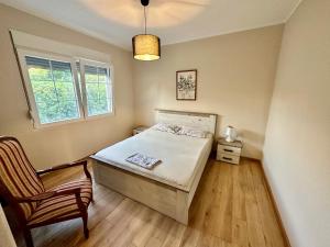 Un dormitorio con una cama y una silla y una ventana. en Sunny village, pool house, en Podgorica 27 fotos más
