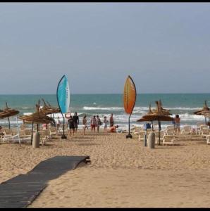 ein Strand mit Sonnenschirmen und Stühlen sowie Menschen am Strand in der Unterkunft Apartamento in Saidia 