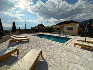 een zwembad met twee banken en een huis bij Sunny village, house with pool in Podgorica