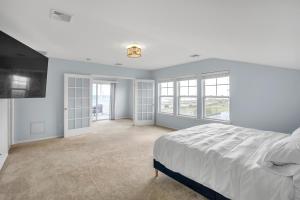 a white bedroom with a large bed and windows at Stunning Beachfront Queens Getaway townhouse in Far Rockaway