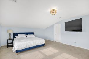 a white bedroom with a bed and a flat screen tv at Stunning Beachfront Queens Getaway townhouse in Far Rockaway