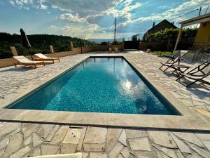 een zwembad met blauw water in een tuin bij Sunny village, house with pool in Podgorica