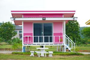 una casa rosa con una mesa de picnic delante de ella en ณ กาญโฮม, en Ban Hin Hak