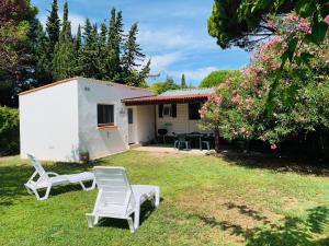 a yard with two chairs and a house at Mobil Home + dépendance dans jolie parc privé in Sérignan