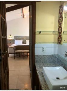 a bathroom with a sink and a bedroom with a bed at Casa Verde Apart - Aptos e Casa Residencial in Praia do Forte