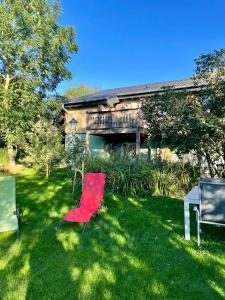 einem roten Stuhl im Gras vor einem Haus in der Unterkunft Ferienhaus Thelen in Niederhersdorf