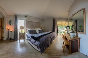 1 dormitorio con cama, mesa y ventana en Treebia Self-catering - Loadshedding Free, en Plettenberg Bay