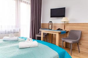 コウォブジェクにあるApartamenty PROMENADA-Arkaのベッド2台、デスク、テレビが備わるホテルルームです。