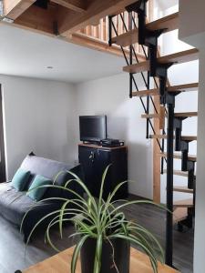 a living room with a couch and a spiral staircase at Maison proche gare et commodités in Le Mans