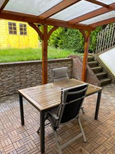 uma mesa de madeira e uma cadeira debaixo de uma pérgola em Wohnung mit Garten und überdachter Terrasse em Bremen