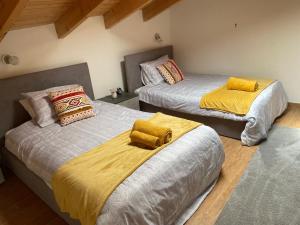 duas camas com lençóis amarelos num quarto em Charming two bedroom house em Strevi