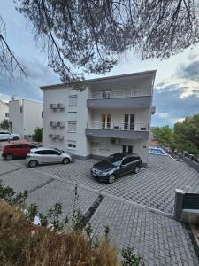 un bâtiment avec deux voitures garées dans un parking dans l'établissement Villa BOTIĆ, à Trogir