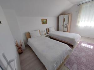 2 Betten in einem Zimmer mit weißen Wänden und einem Fenster in der Unterkunft Kuća-Villa pored rijeke i jezera Čelebići Konjic in Konjic