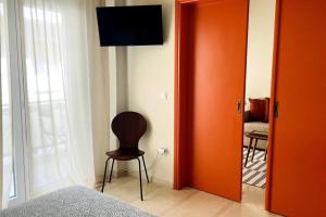Un dormitorio con una puerta naranja y una silla en una habitación en Cybele apt downtown, en Volos