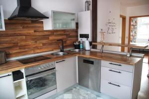 eine Küche mit weißen Schränken und einer Holzwand in der Unterkunft Brockensicht in Ilsenburg