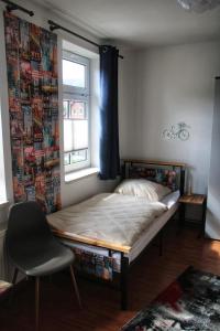 Bett in einem Zimmer mit Fenster und Stuhl in der Unterkunft Brockensicht in Ilsenburg