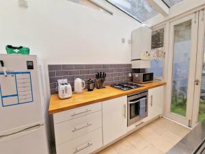 a kitchen with white cabinets and a white refrigerator at Beautiful Hyde Park Flat by Lancaster Gate Station with Private Back Patio in London
