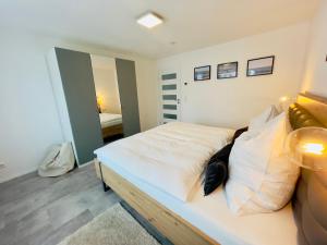 een slaapkamer met een bed met witte lakens en een spiegel bij Frevor - DESIGN L - I in Ulm