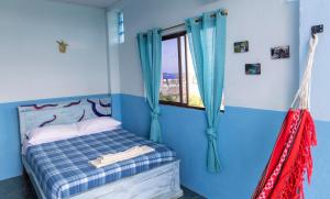 sypialnia z łóżkiem z niebieskimi ścianami i oknem w obiekcie Mango Tree w mieście San Cristóbal