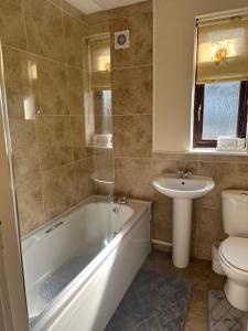 a bathroom with a tub and a toilet and a sink at Stunning cozy three bedroom house near ARI in Aberdeen