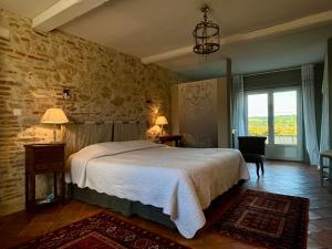 a bedroom with a bed and a stone wall at Le Mas De Marie in Lavaur